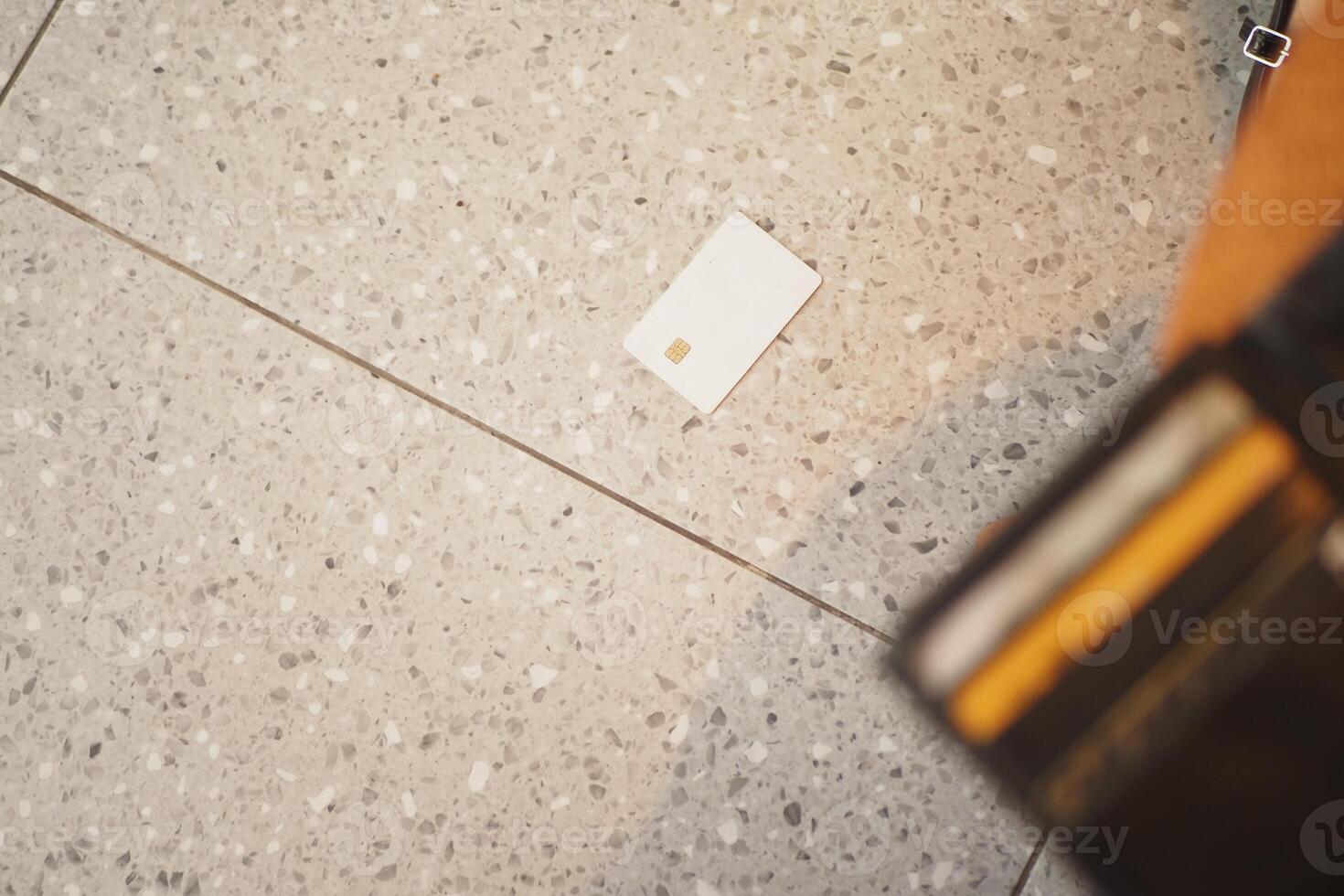 Card dropped on tiled floor near wallet during busy day photo