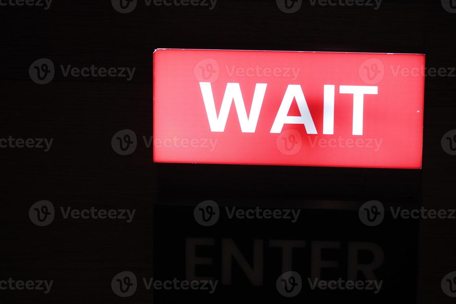 Bright red wait sign illuminating entry point at night photo
