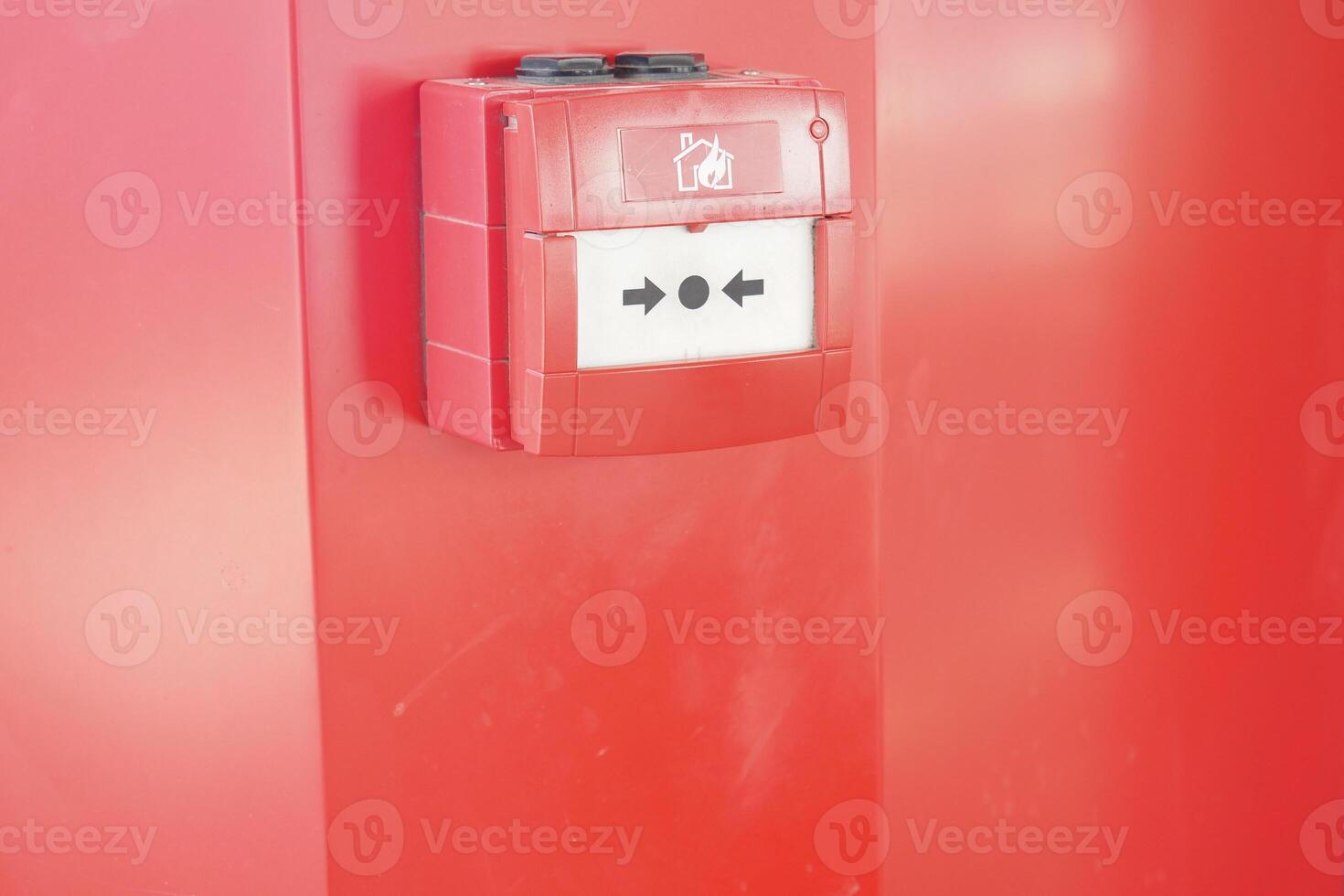 Fire alarm box mounted on a bright red wall indoors photo