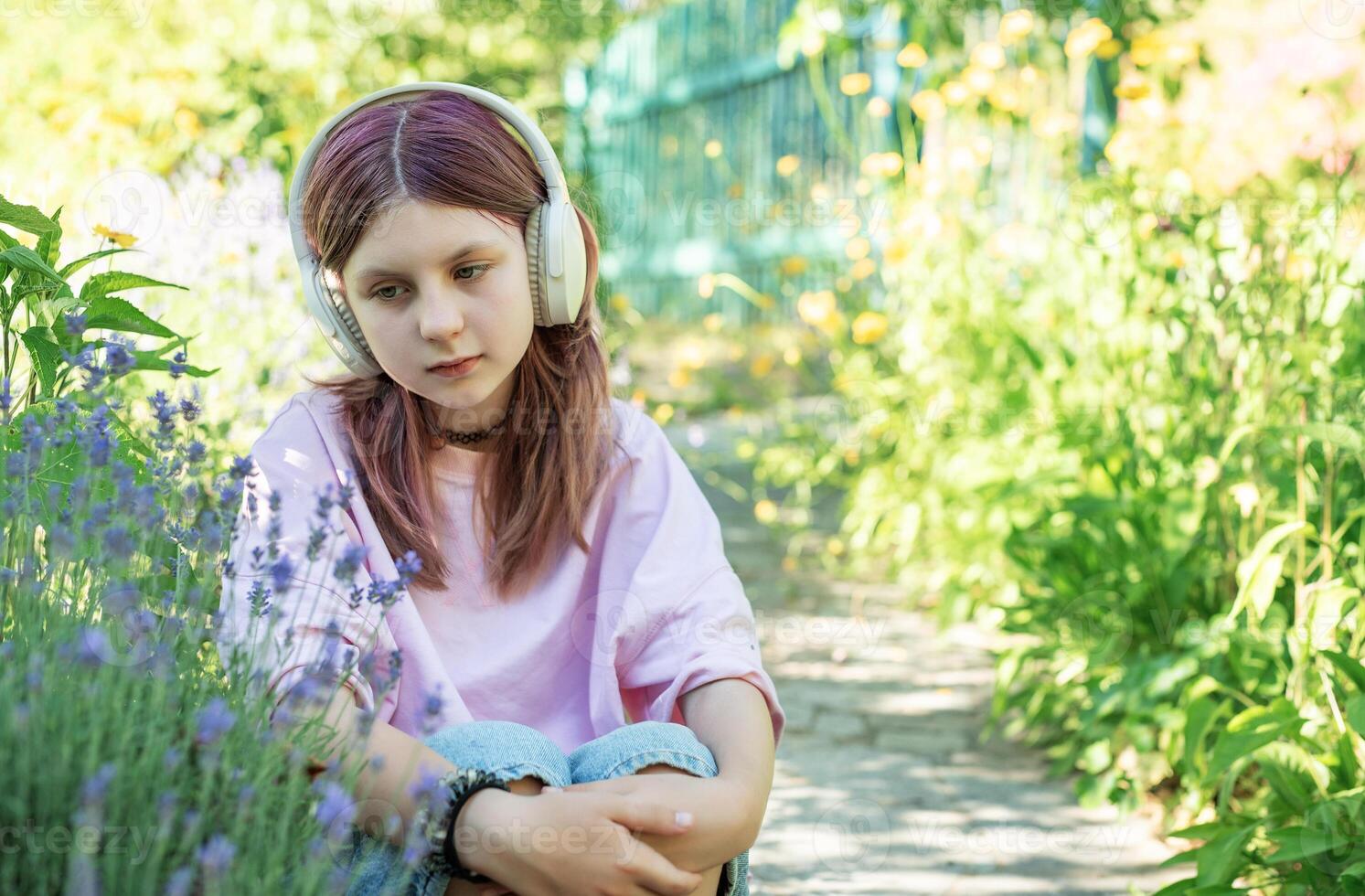 Teenager girl listening music with her headphones in garden photo