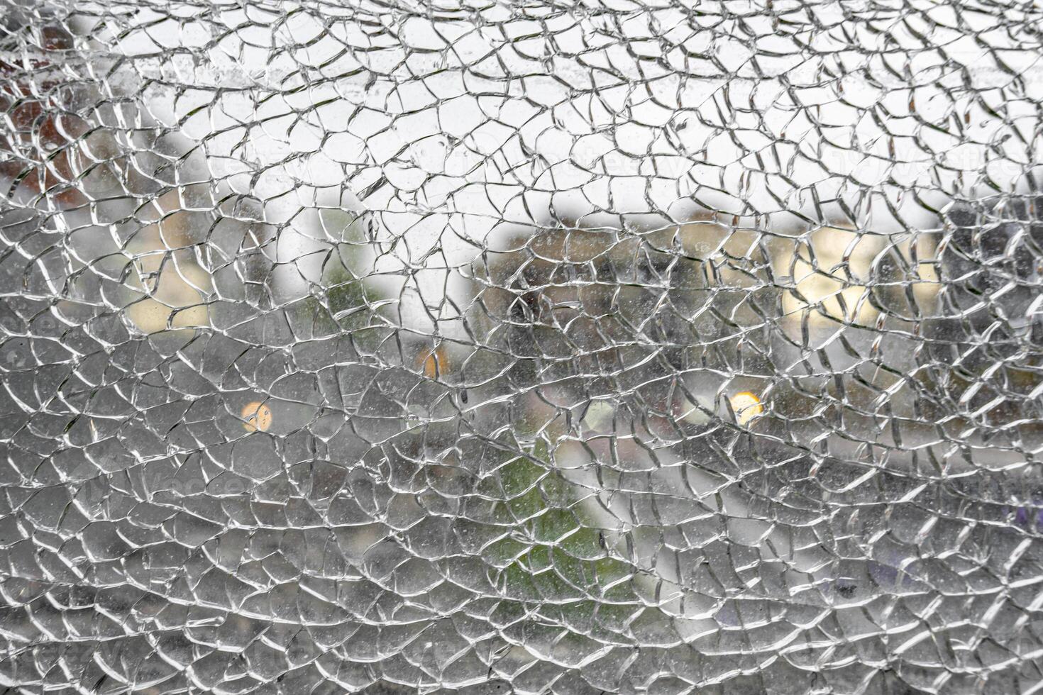 Shattered glass window forming intricate web like cracks photo