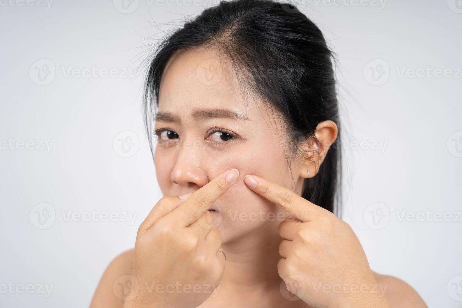 Asian woman squeezing pimples on her face, skin care lifestyle concept. photo