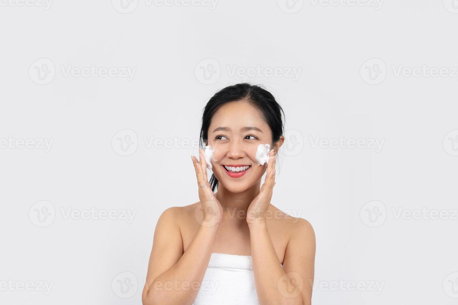 Smiling woman washing face with facial foam photo
