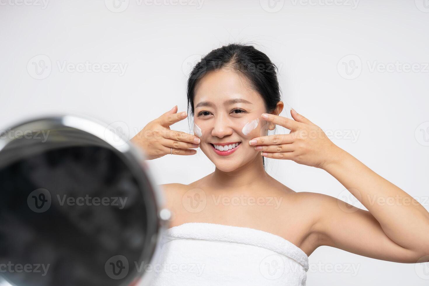 A woman is applying moisturizer before makeup, home cosmetic routine photo
