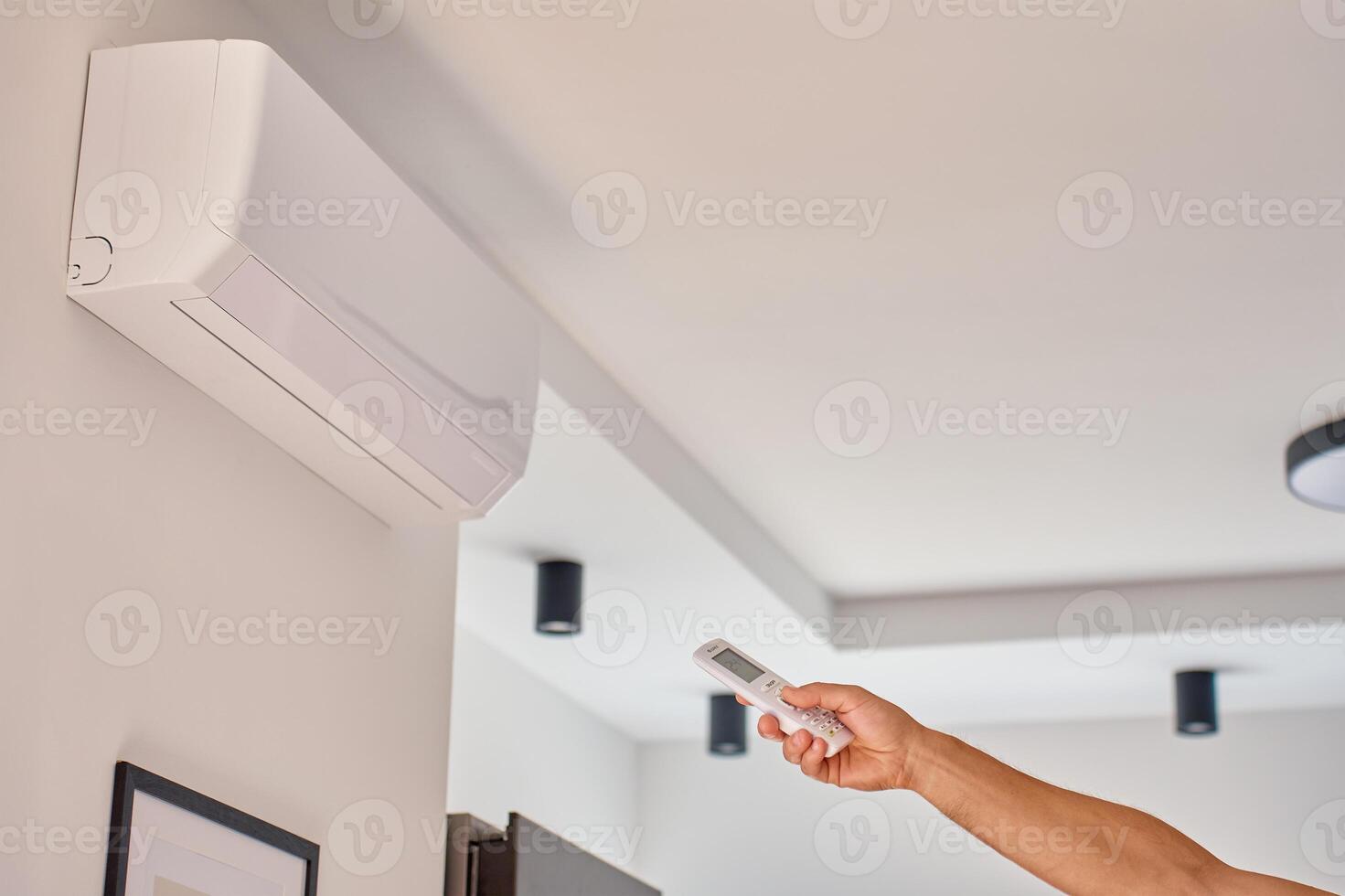 Close up of hand using remote control to adjust temperature on air conditioner photo