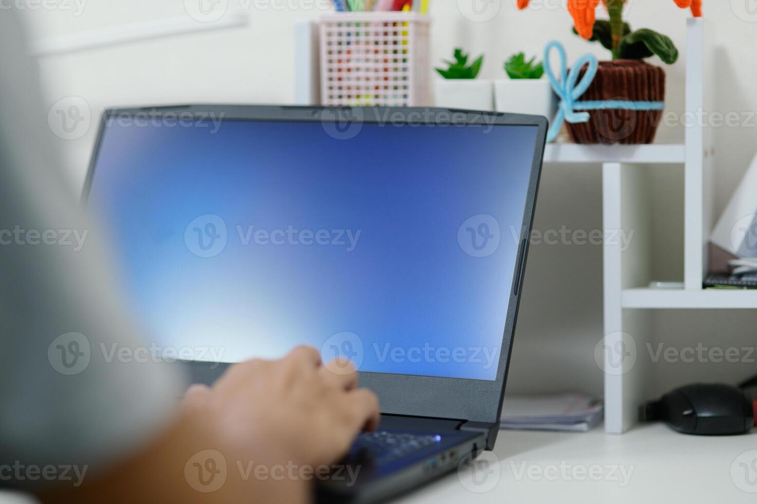 Person working on laptop in modern office workspace with plants photo