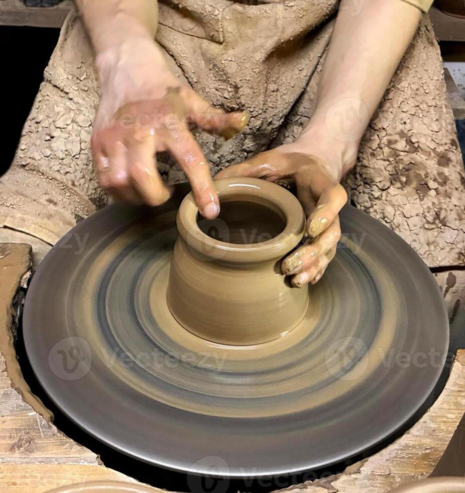 Hands of master shape clay pot on a potters wheel. Closeup. photo