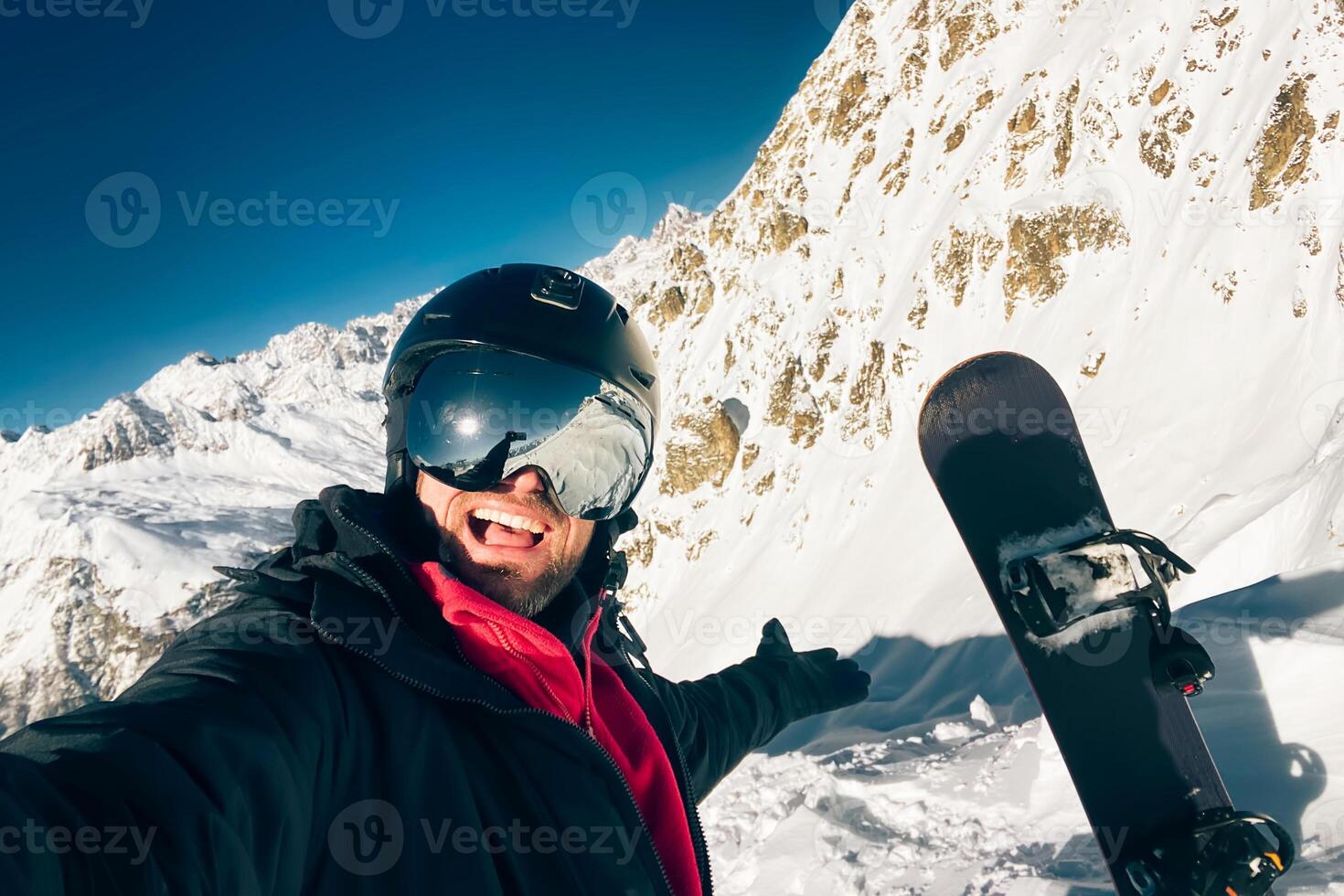 Happy excited snowboarder taking a selfie after reaching top before freeriding in caucasus mountains outdoors winter photo