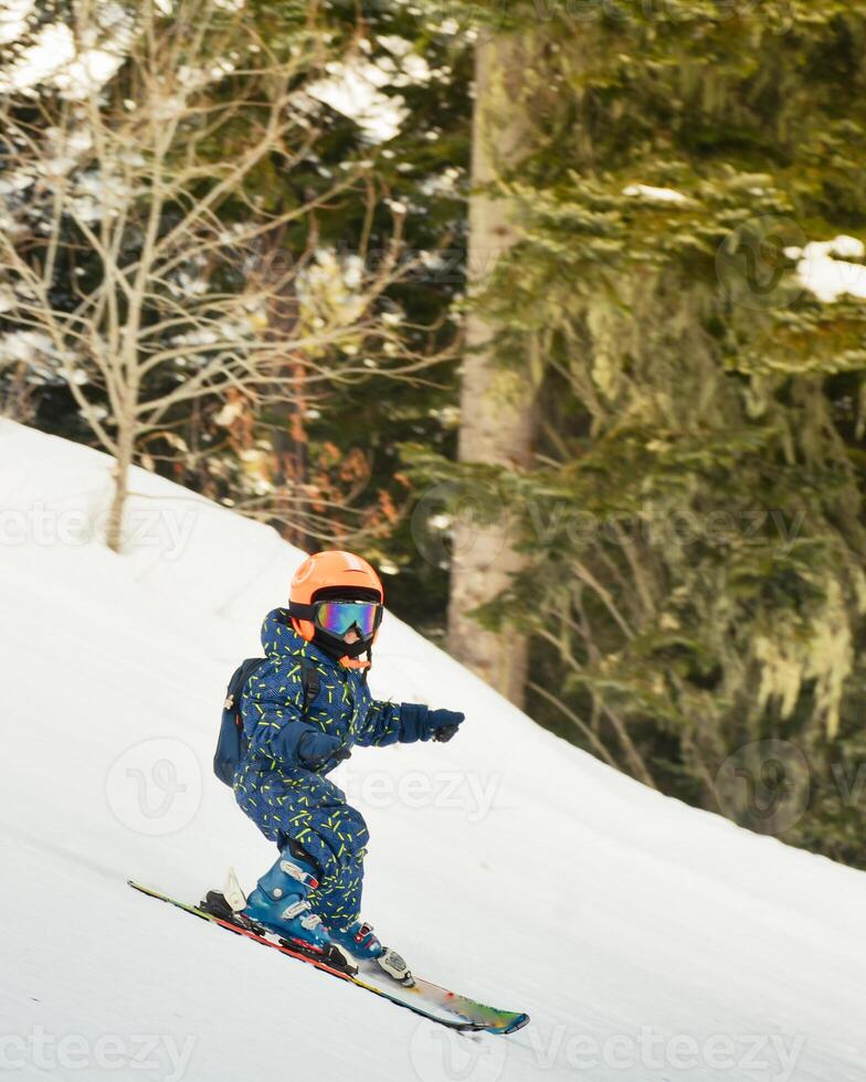 Close up cute little brave unrecognizable boy ski downhill on slope in winter ski resort. Active lifestyle winter holidays with kids concept photo