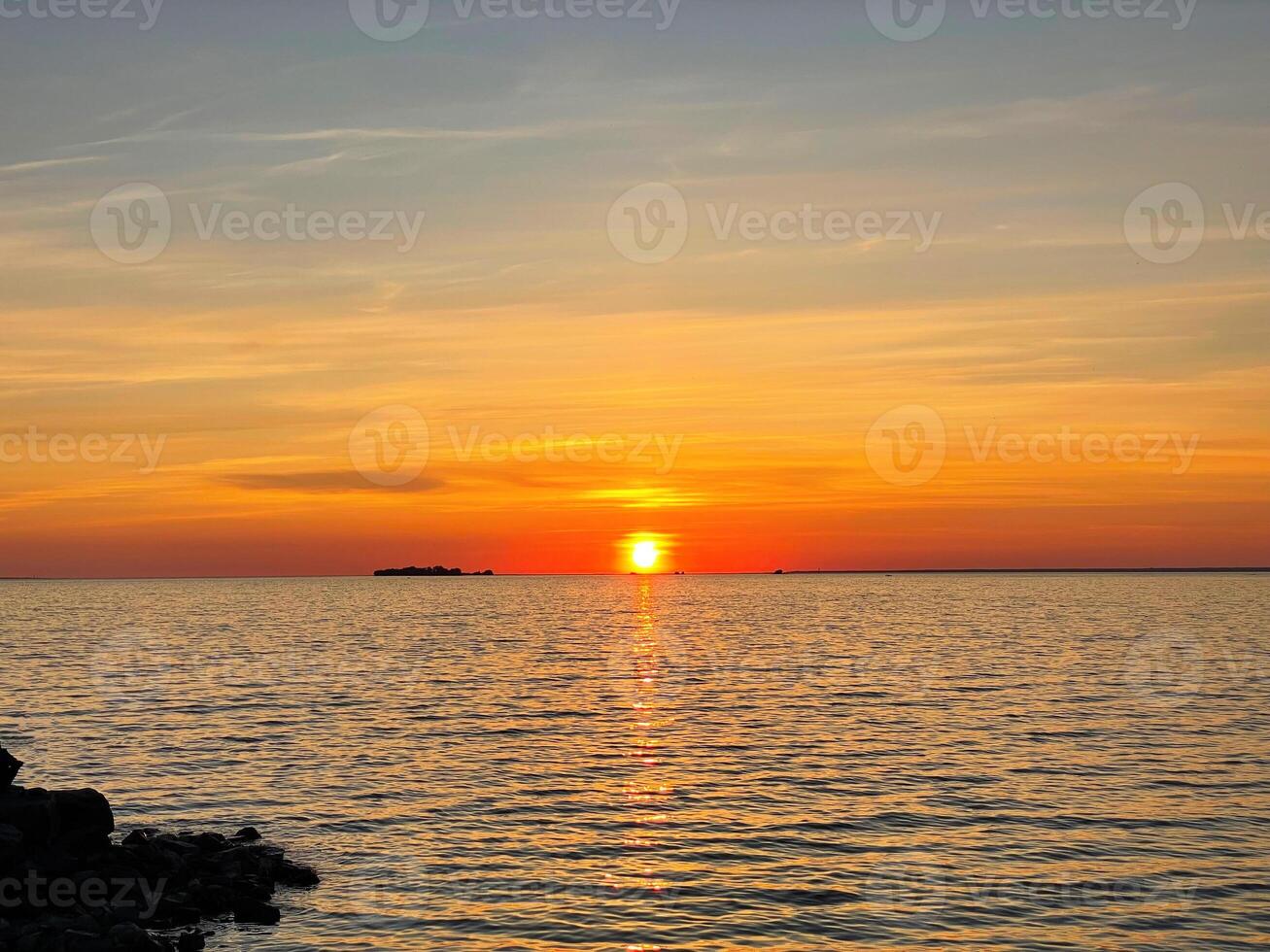 Serene sunset over the sea. The sun sets on the water. The sky is painted with bright colors. Sunny path on the water. Summer evening et sunset beach. photo