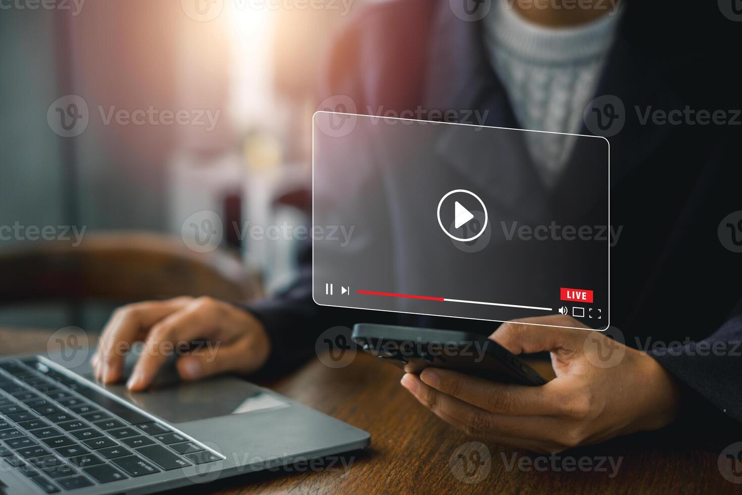 A person interacts with streaming technology on a laptop and smartphone, showcasing a futuristic digital interface. photo