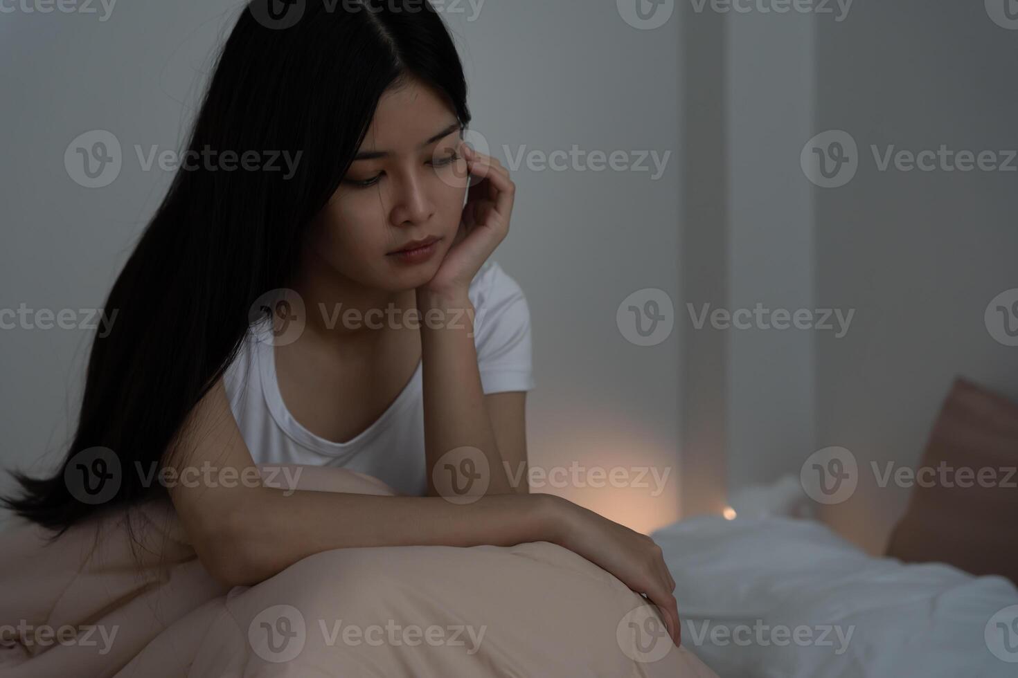 asian woman in bed late trying to sleep suffering insomnia, sleepless or scared in a nightmare, looking sad worried and stressed. Tired and headache or migraine waking up in the middle of the night photo
