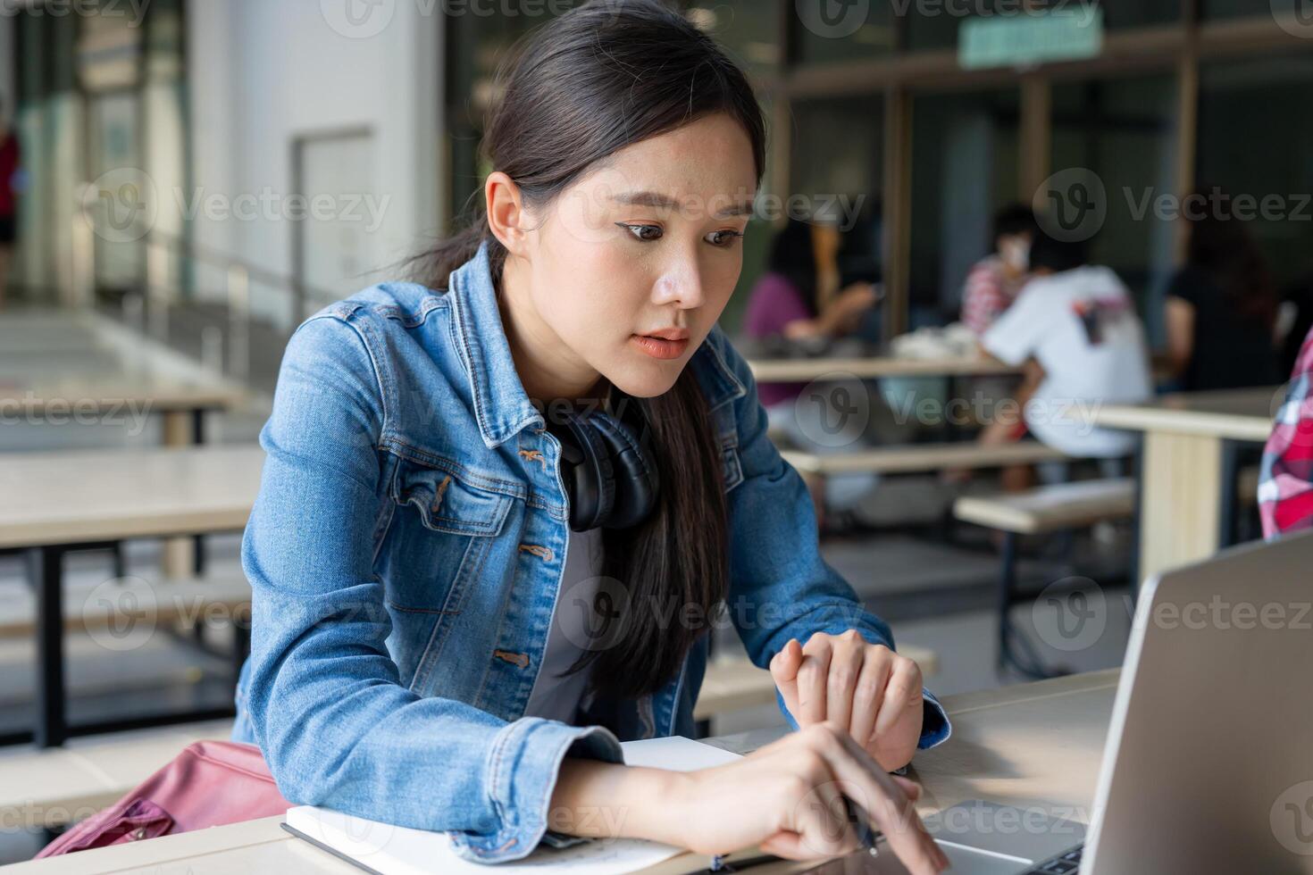 Asian woman female student excited checking language test results on laptop. Smile girl happy study online. book in college campus. Portrait female on international Asia University. Education, study, photo