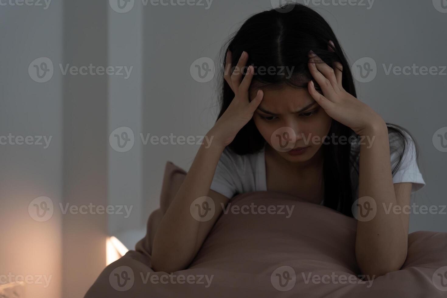 asian woman in bed late trying to sleep suffering insomnia, sleepless or scared in a nightmare, looking sad worried and stressed. Tired and headache or migraine wake up in the middle of the night photo