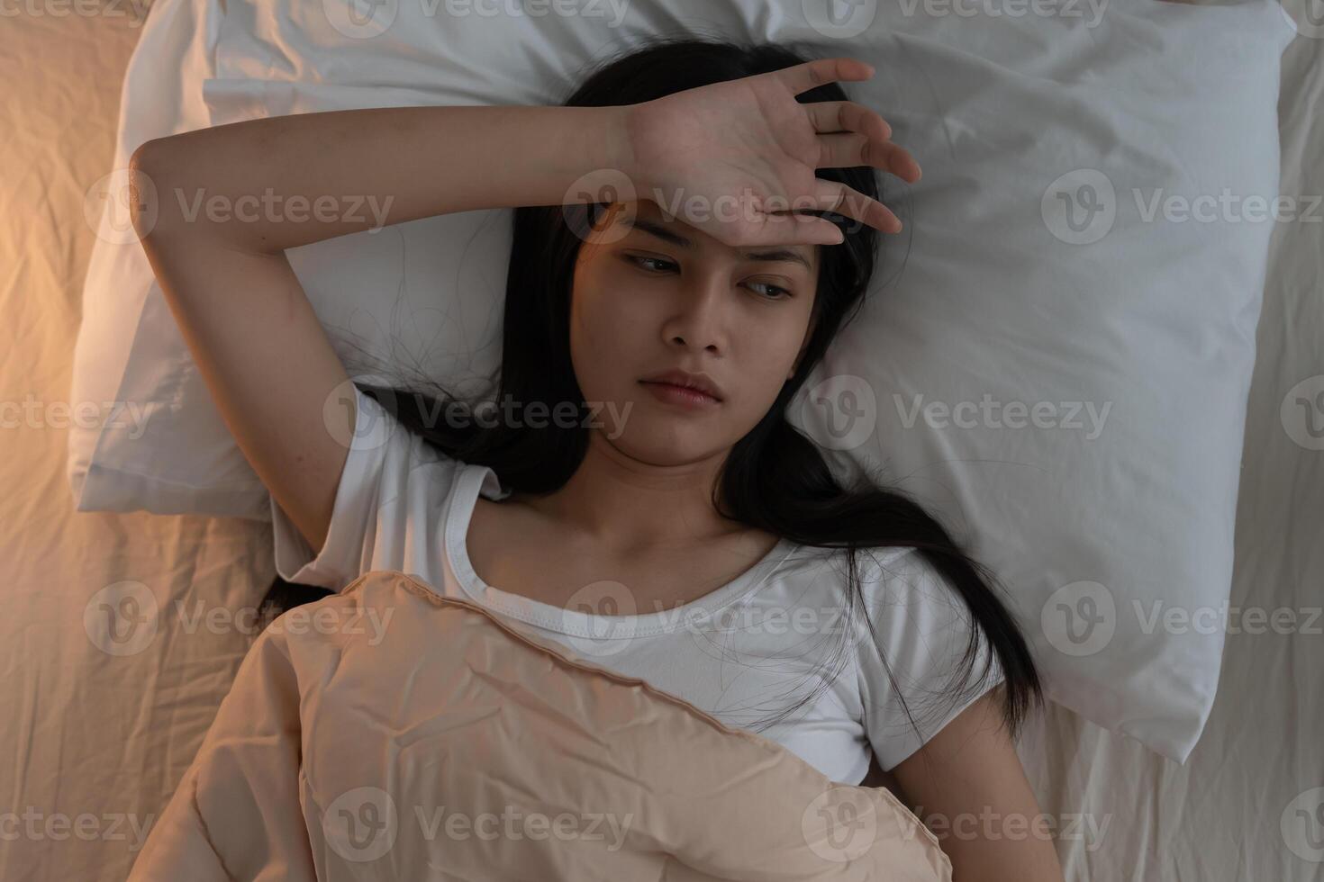 woman in bed late trying to sleep suffering insomnia, sleepless or scared in a nightmare, looking sad worried and stressed. Tired and headache or migraine waking up in the middle of the night photo