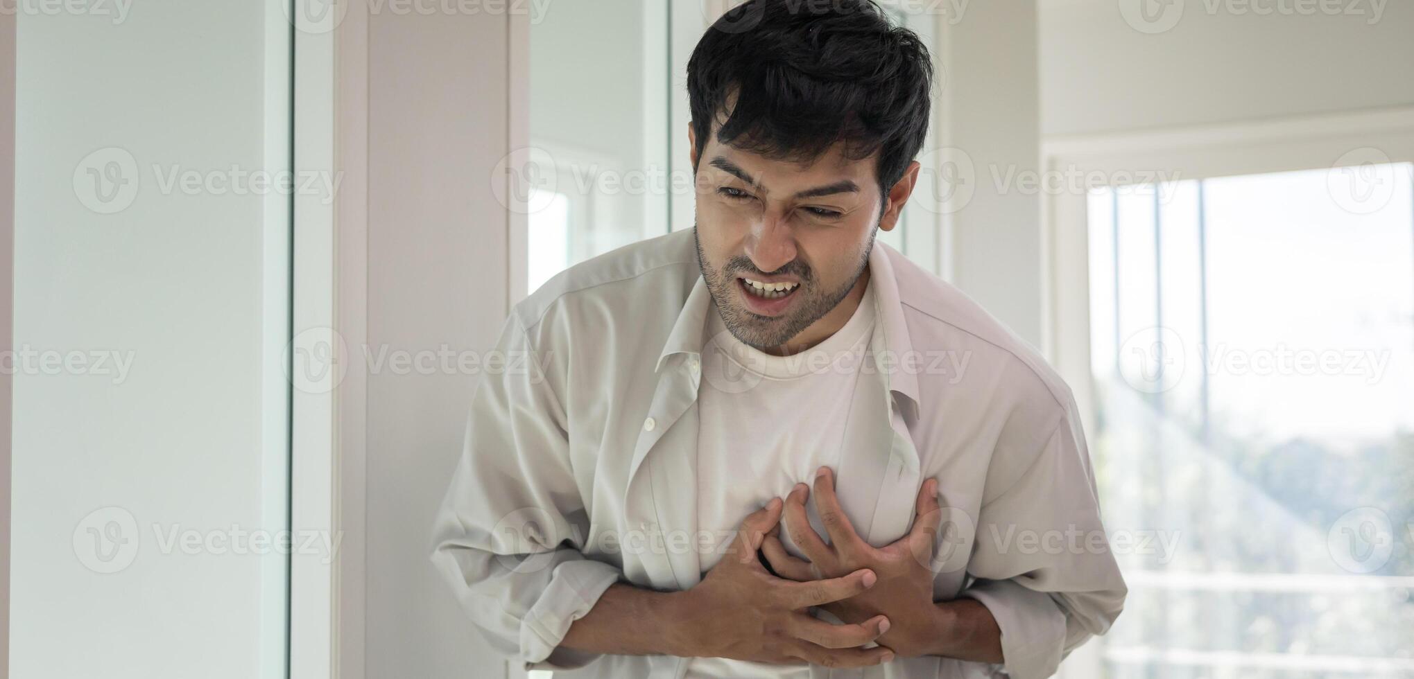 hold chest with heart attack symptoms. asian man have chest pain caused by heart disease, leak, dilatation, enlarged coronary heart, press on the chest with a painful expression photo