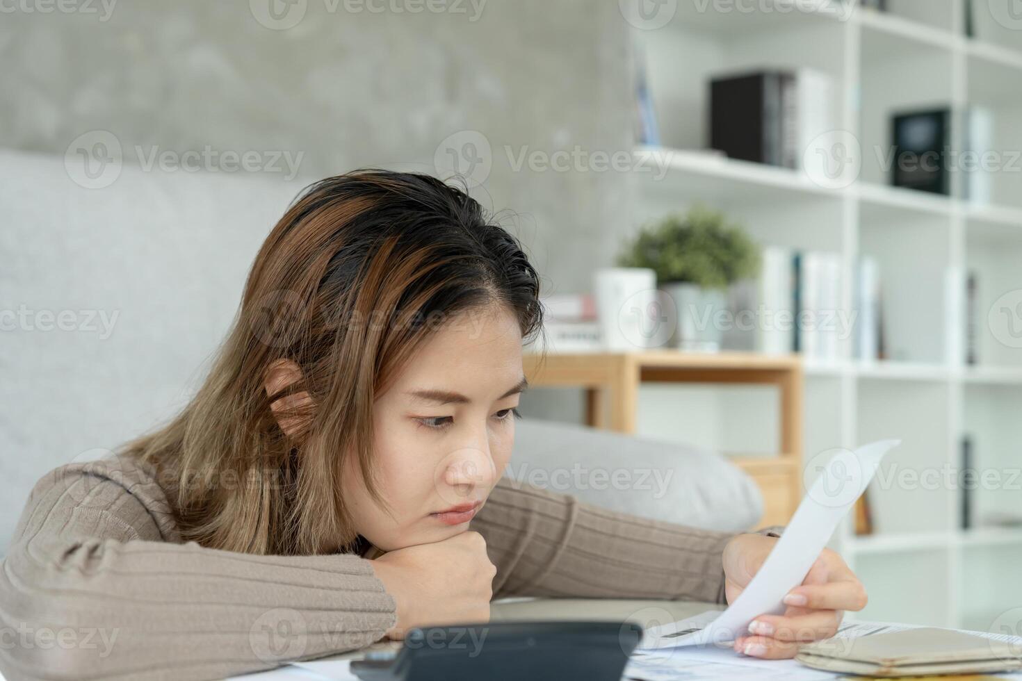 Stressed and headache asian woman with large bills or invoices no money to pay to expenses and credit card debt. shortage, Financial problems, mortgage, loan, bankruptcy. bankrupt, poor. photo