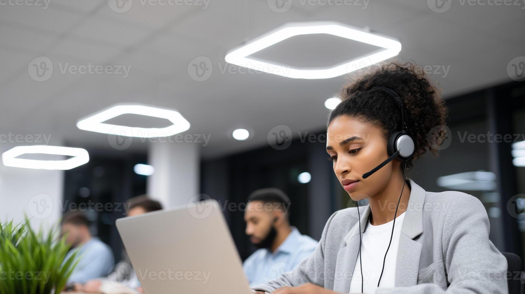 African American woman customer service agent with headset working on laptop in modern call center office. Professional support representative providing client assistance. photo