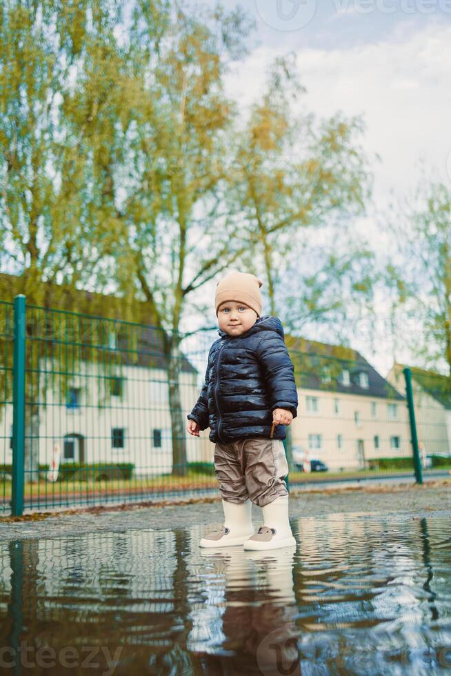 An adorable toddler is truly enjoying a rainy day by splashing around in a puddle while dressed in cozy winter attire. Its moments like these that capture the essence of childhood joy and innocence photo