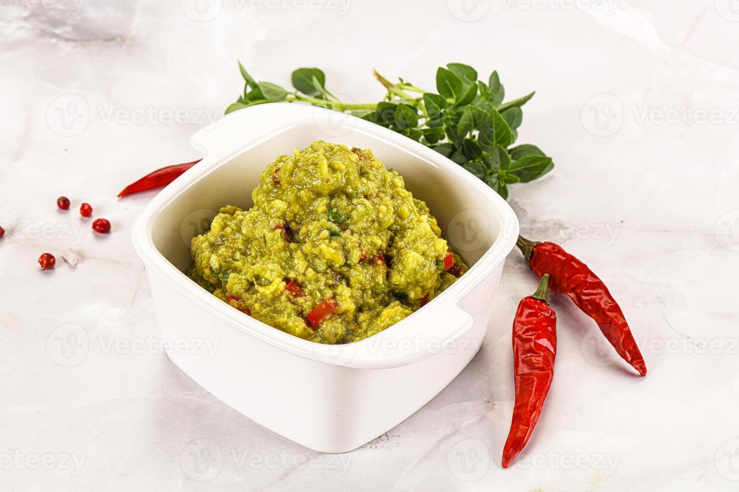 A white bowl with a green sauce and red peppers photo
