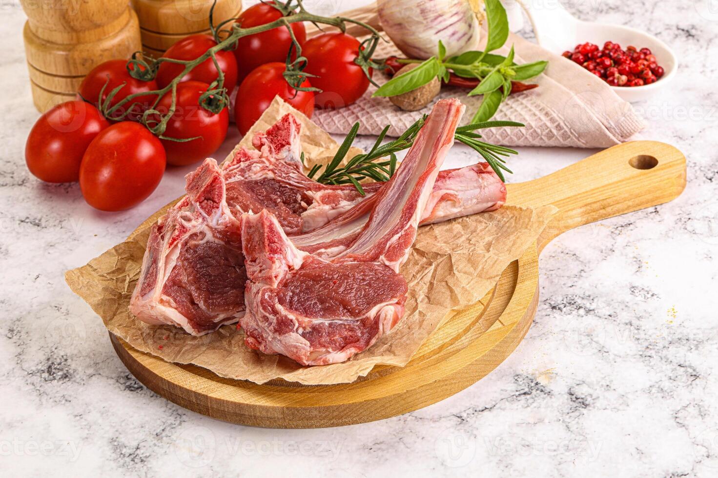 A cutting board with two lamb chops and tomatoes photo