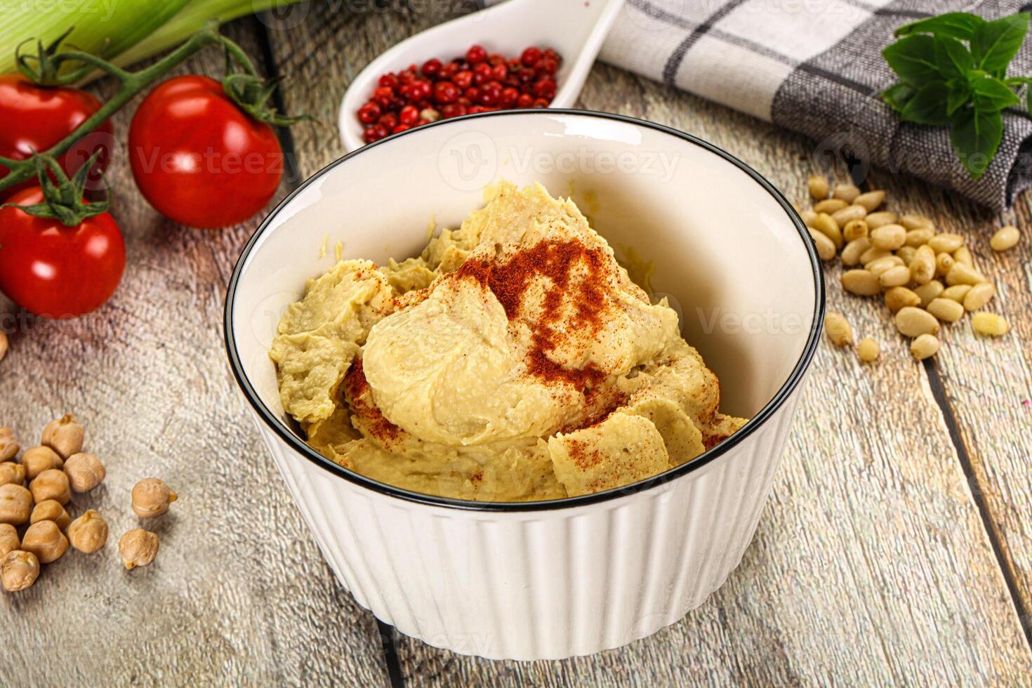 A bowl of hummus with a spoon and other ingredients photo