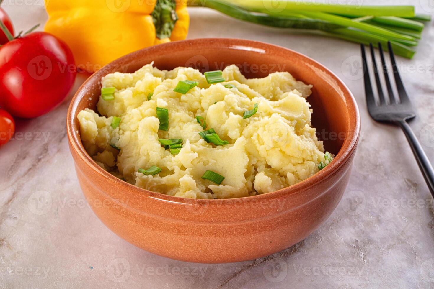A bowl of mashed potatoes with vegetables on a table photo