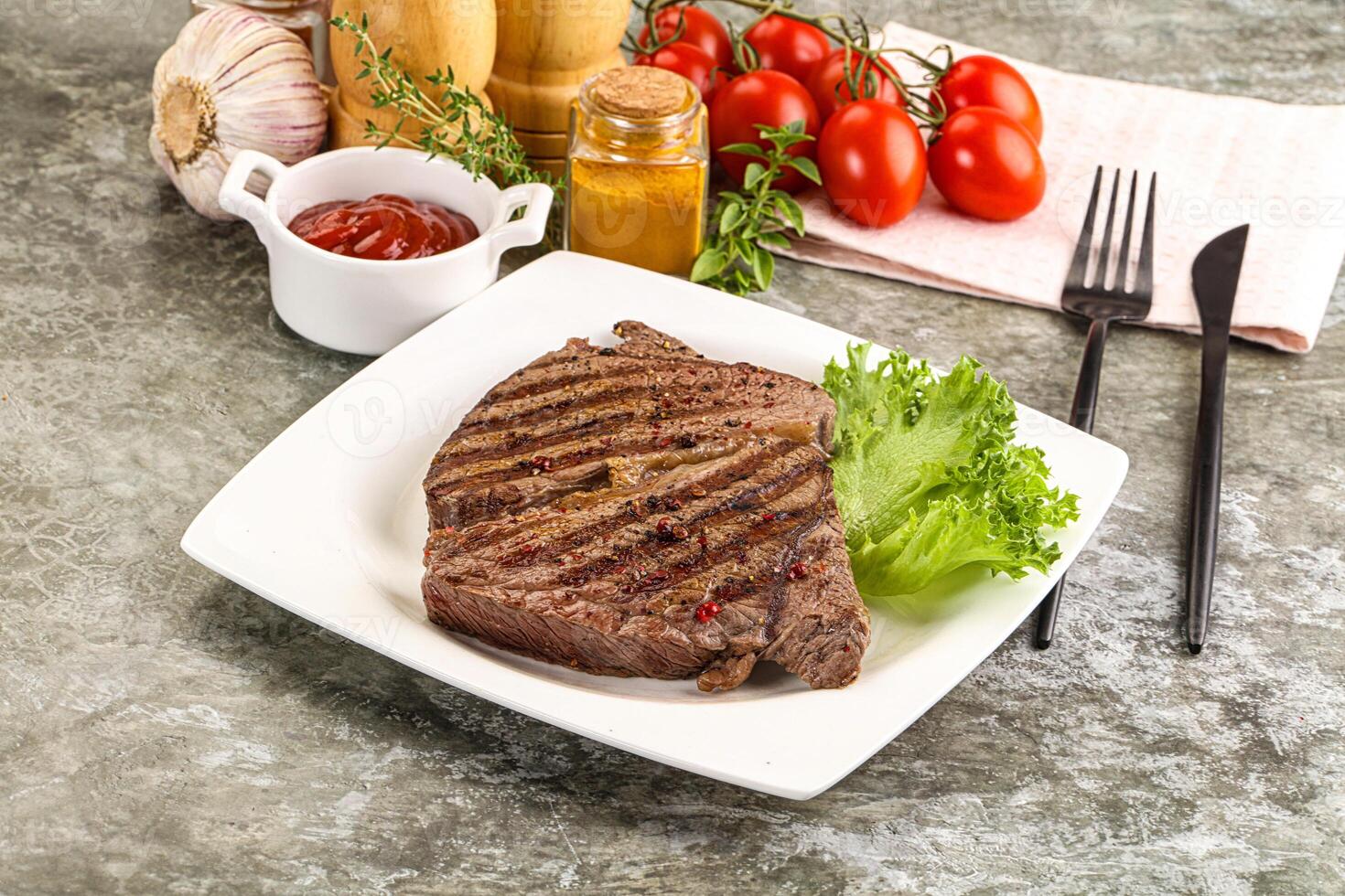 A steak on a plate with tomatoes, lettuce and other ingredients photo
