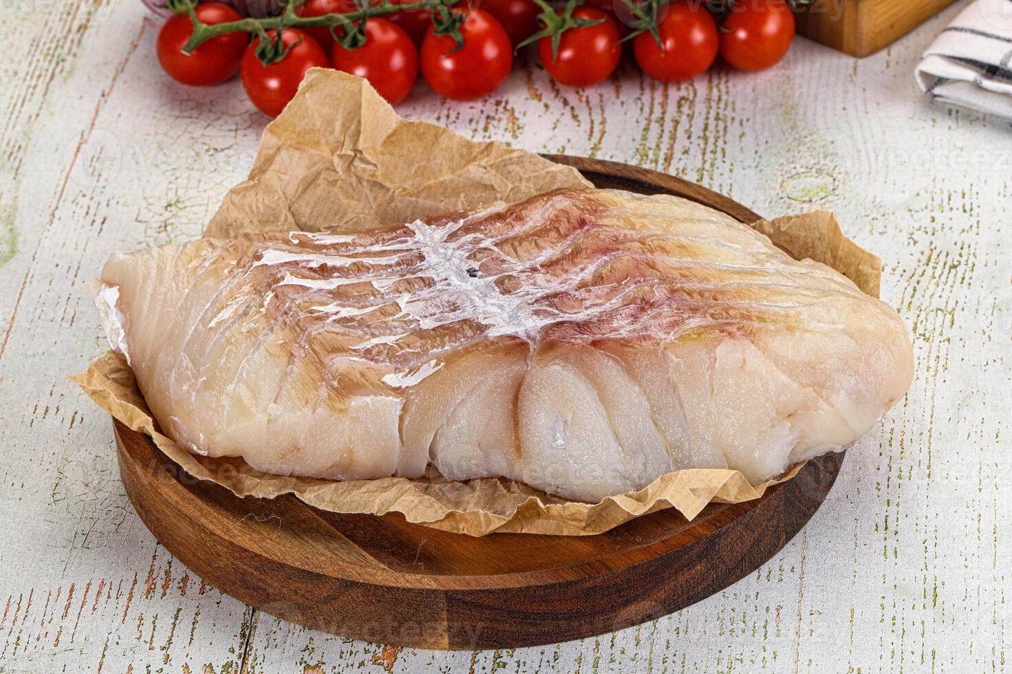 A piece of fish on a wooden plate with tomatoes photo