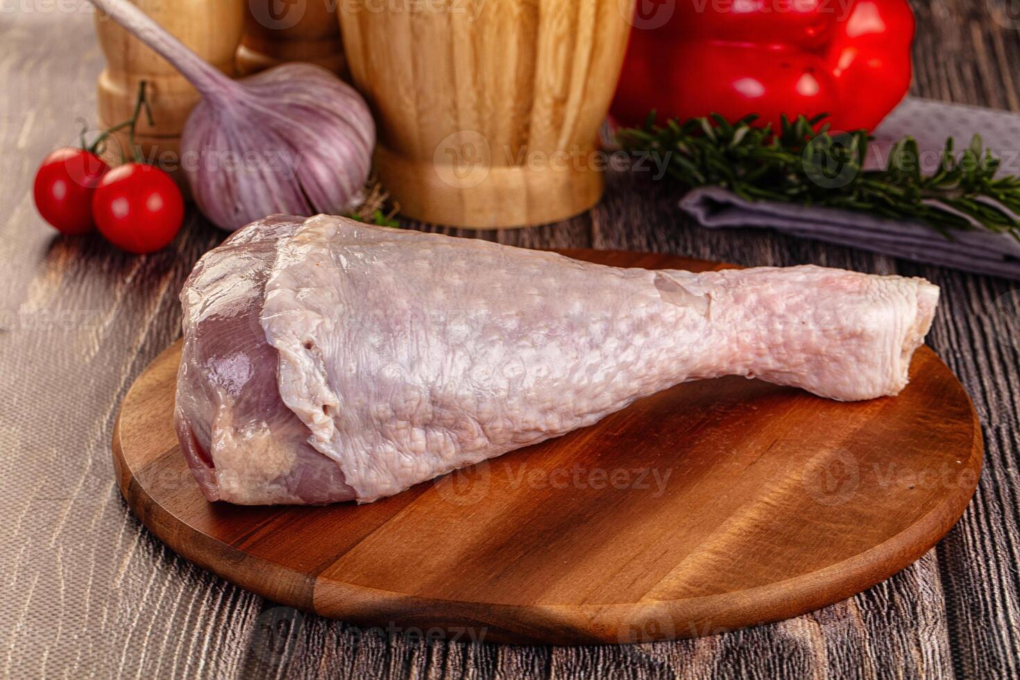 A raw chicken leg on a wooden cutting board photo