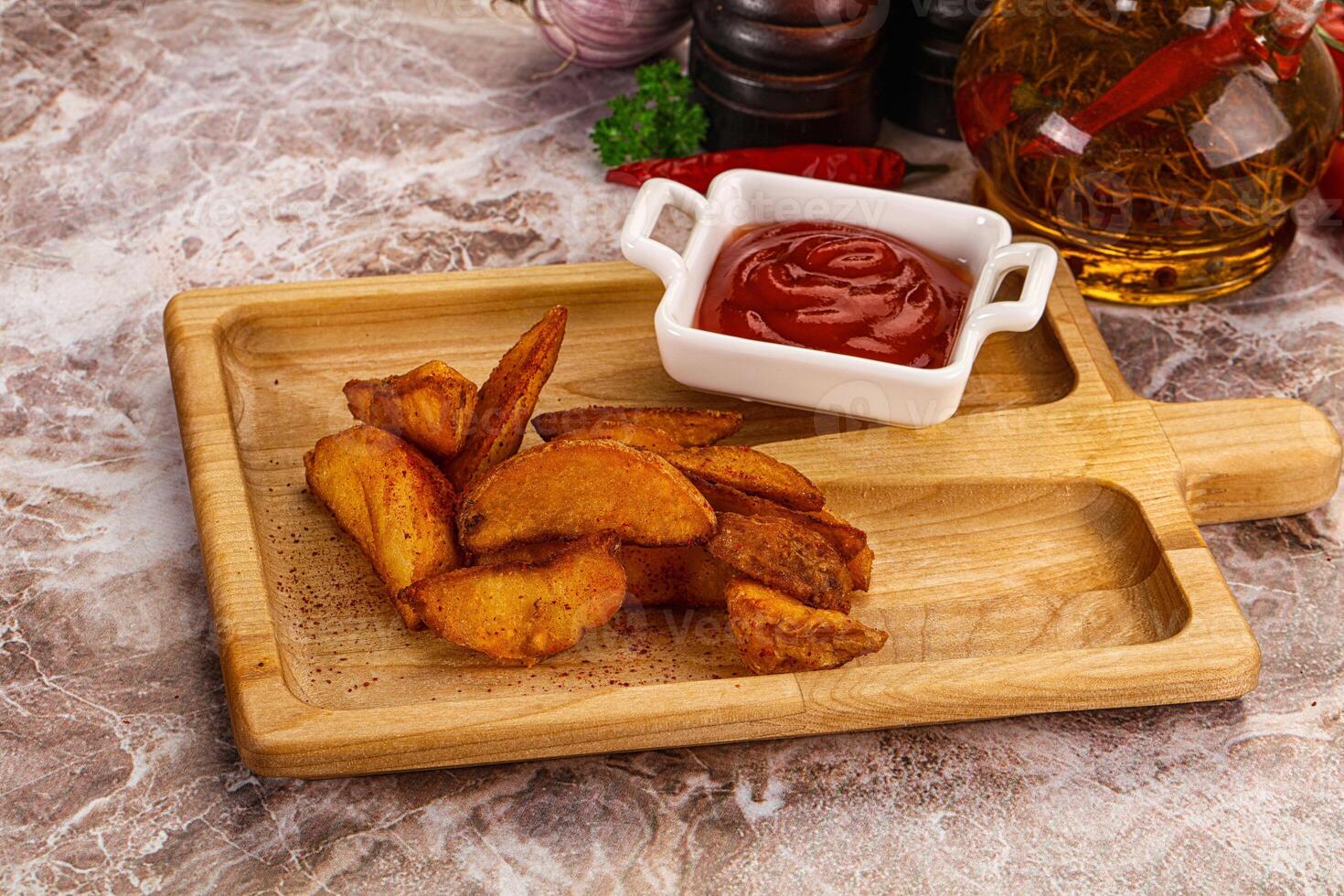A wooden cutting board with some fries and ketchup photo