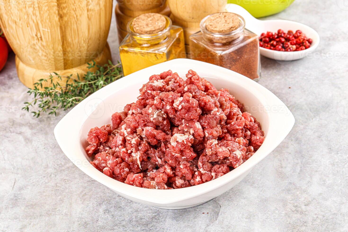 A bowl of ground beef sitting next to a wooden bowl photo
