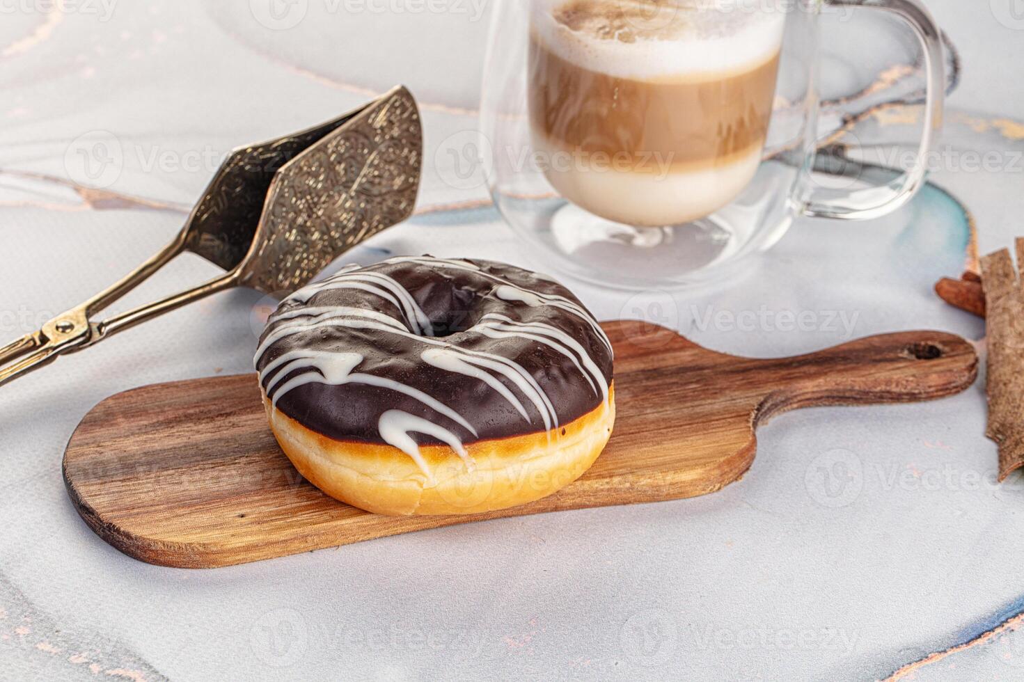 A donut on a wooden board next to a cup of coffee photo