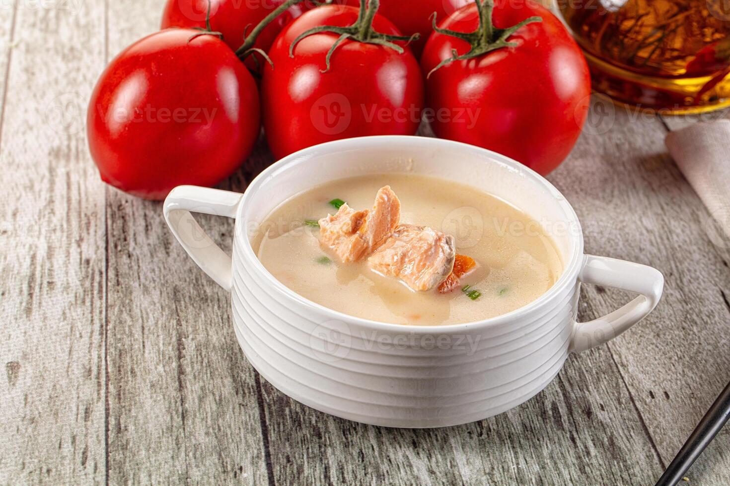A bowl of soup with some tomatoes and a spoon photo