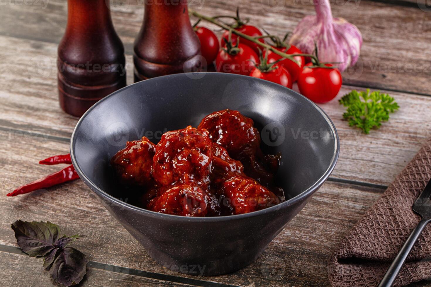 A bowl of meatballs with a bottle of ketchup and a knife photo