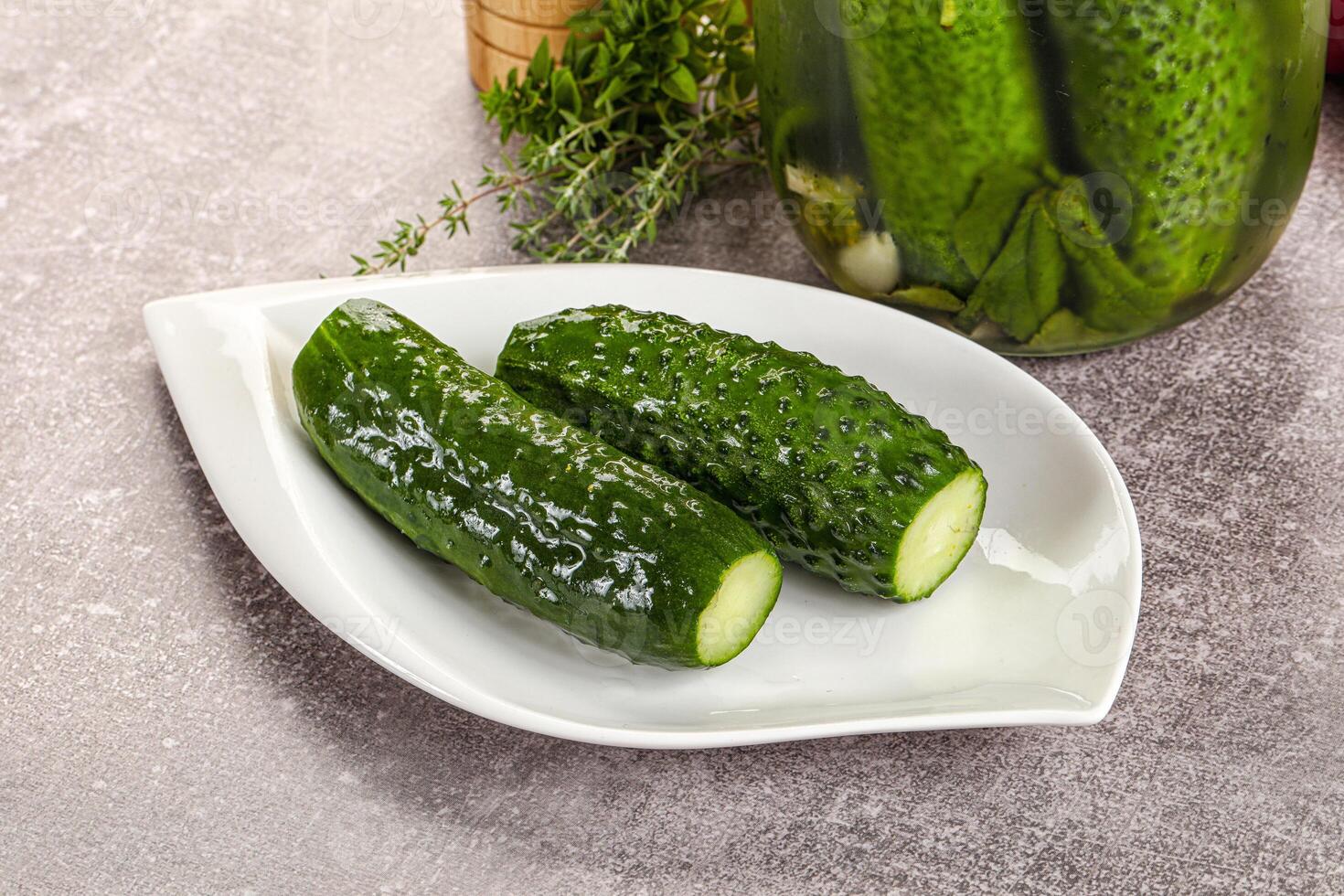A white plate with cucumbers and a jar of pickles photo