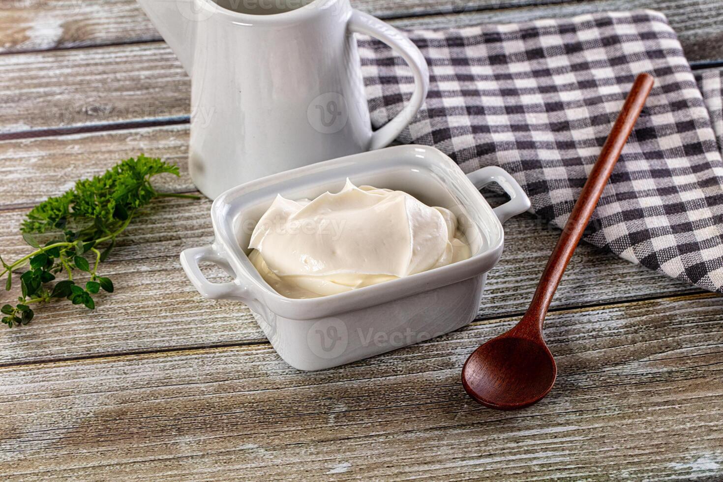 Yogurt in a bowl and spoon on a wooden table photo