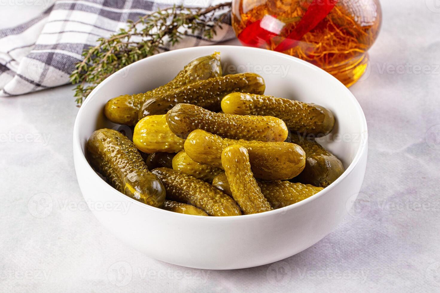 A bowl filled with pickles and a bottle of syrup photo