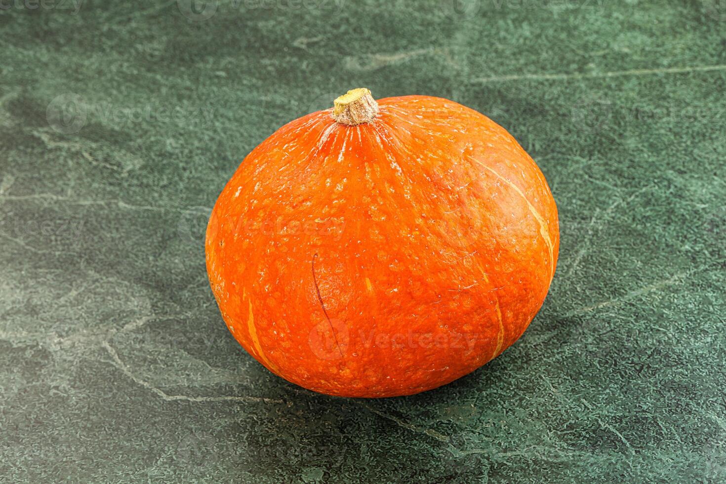 A small orange squash on a green surface photo