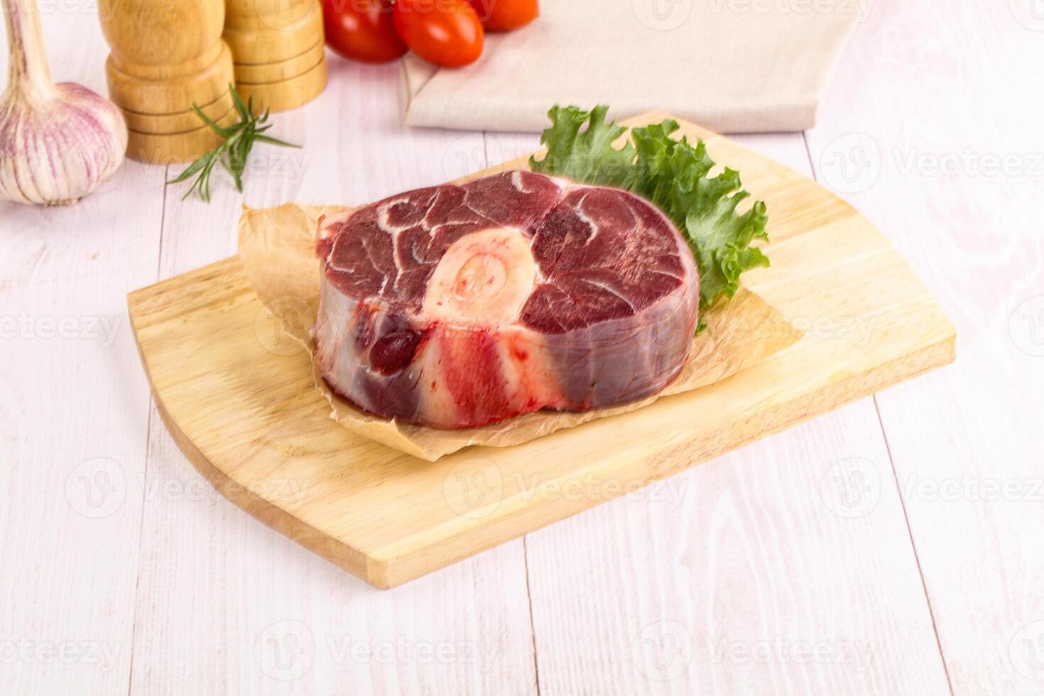 Raw beef on wooden cutting board with vegetables and herbs photo