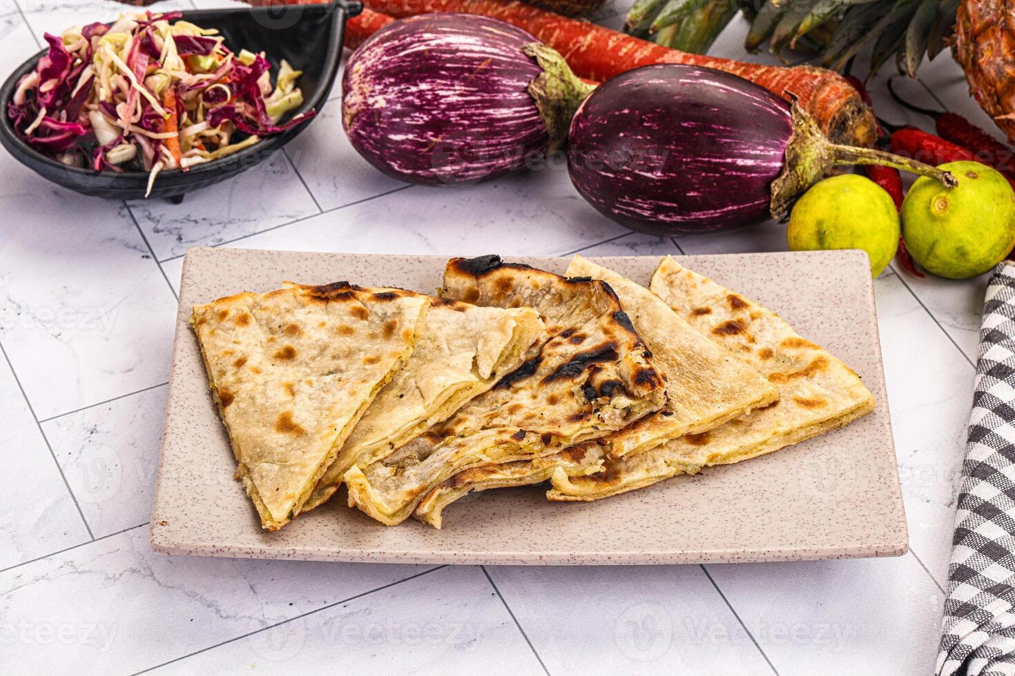 A plate of food with a tortilla, vegetables and a bowl of salad photo