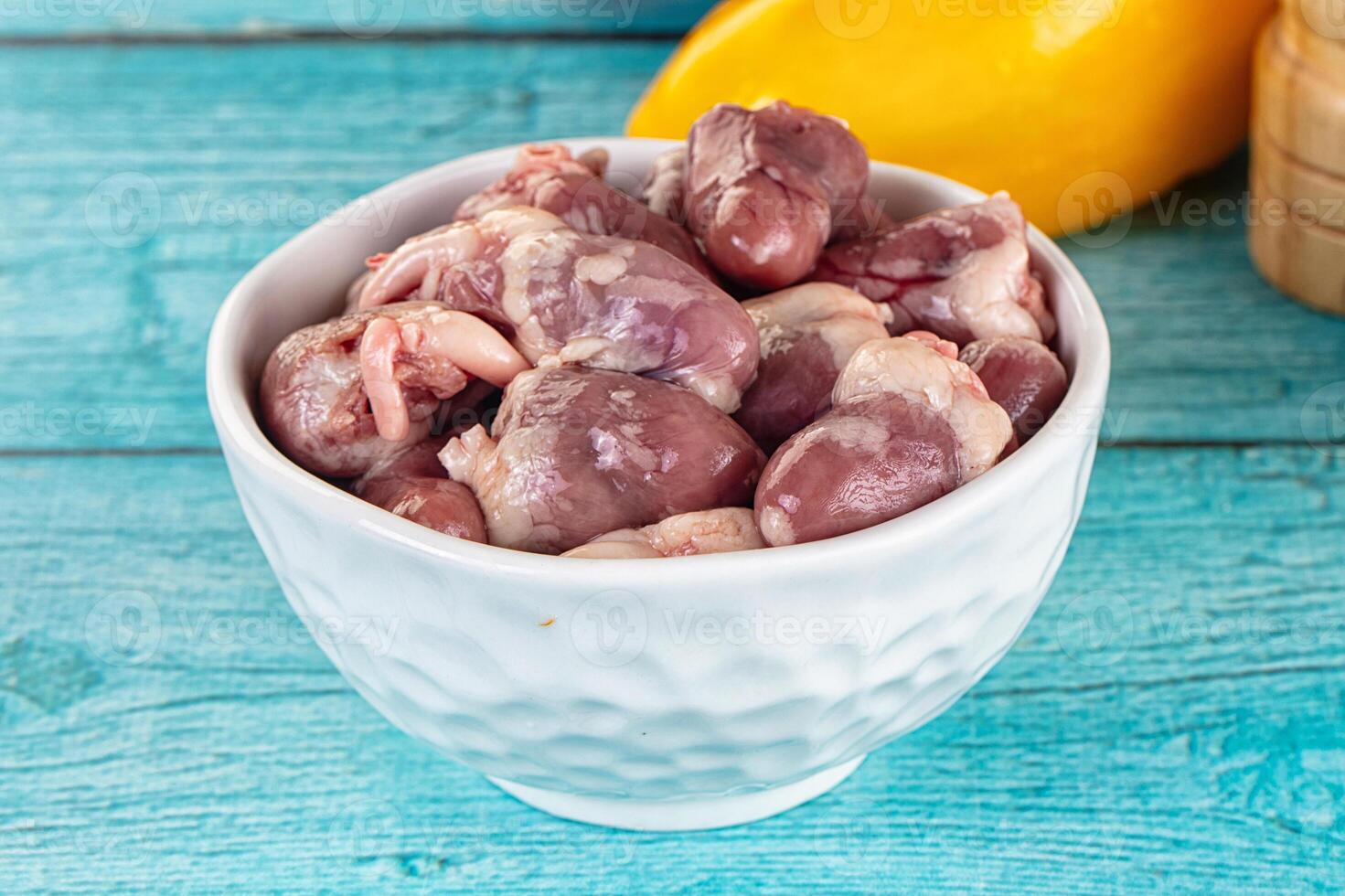 A bowl filled with raw chicken and a lemon photo