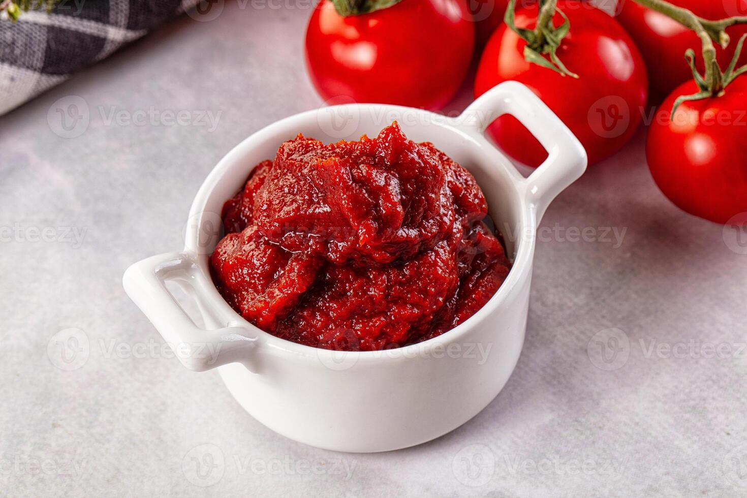 A bowl of tomato sauce next to tomatoes photo