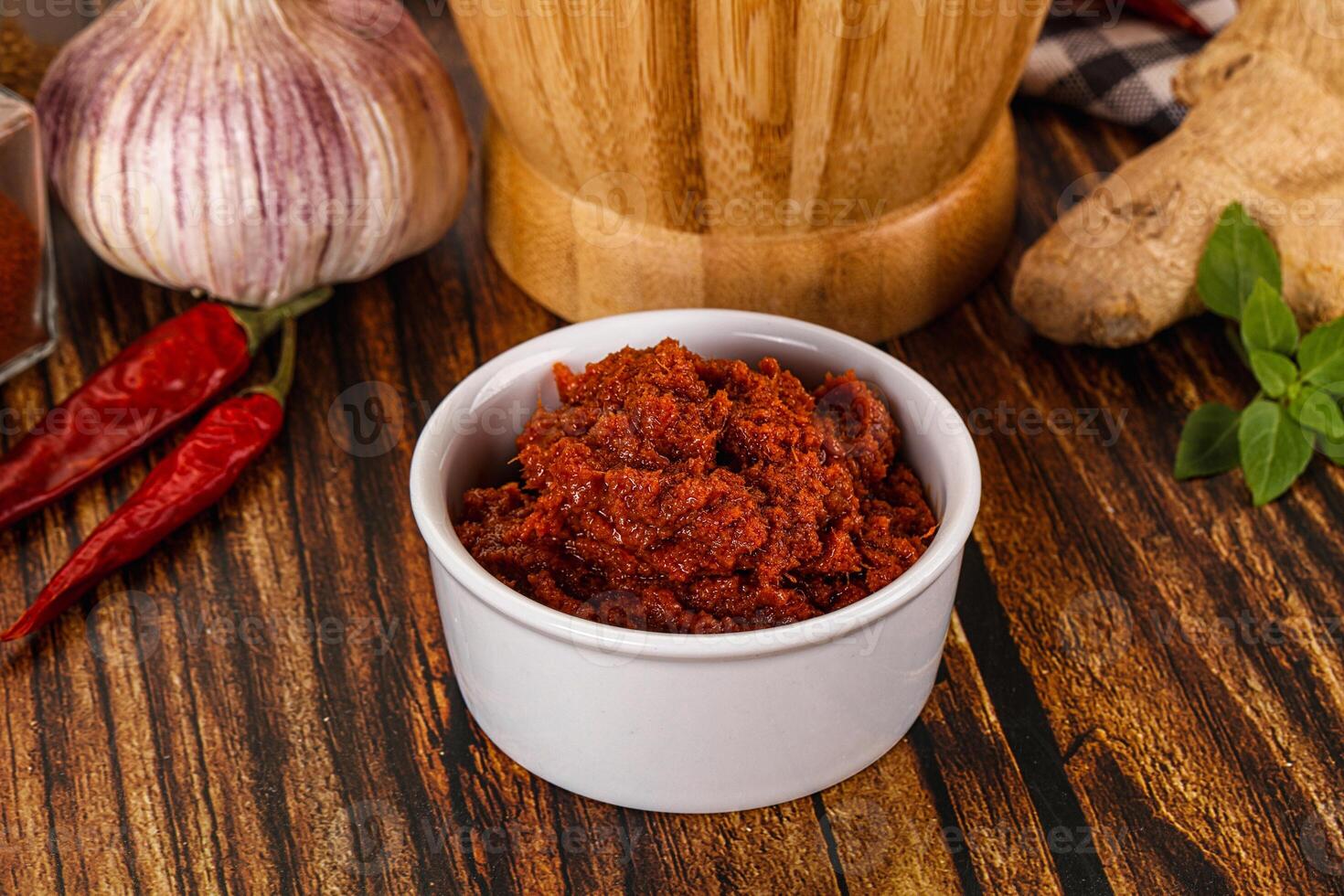 A bowl of chili paste next to a wooden cutting board photo