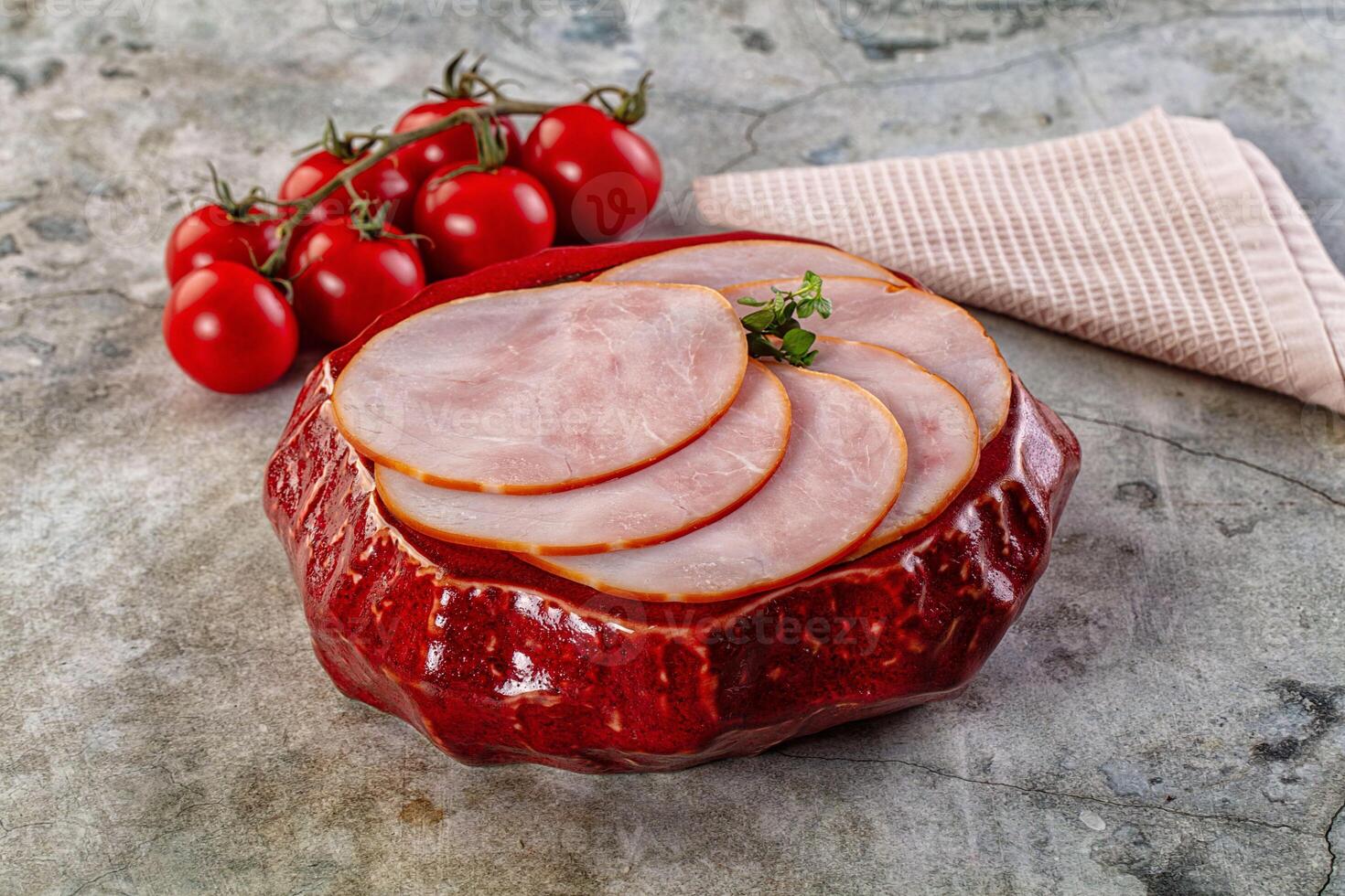 Sliced ham in red bowl with tomatoes on a table photo