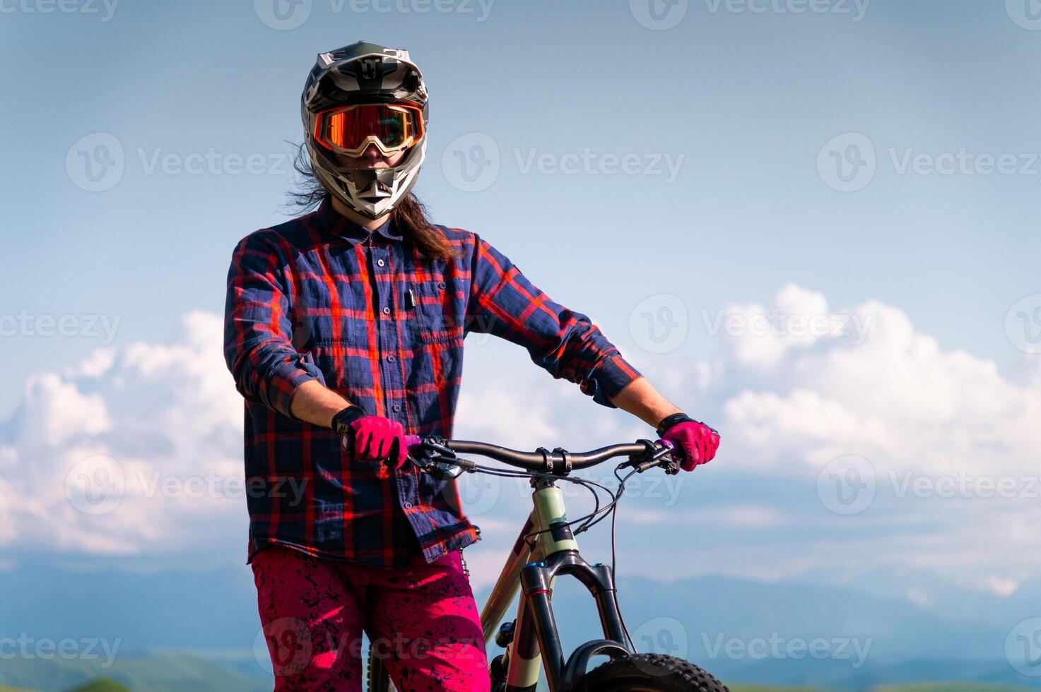 Portrait of a cyclist standing with his bicycle against a dramatic sky with cumulus clouds. Handsome young man biking in the countryside photo