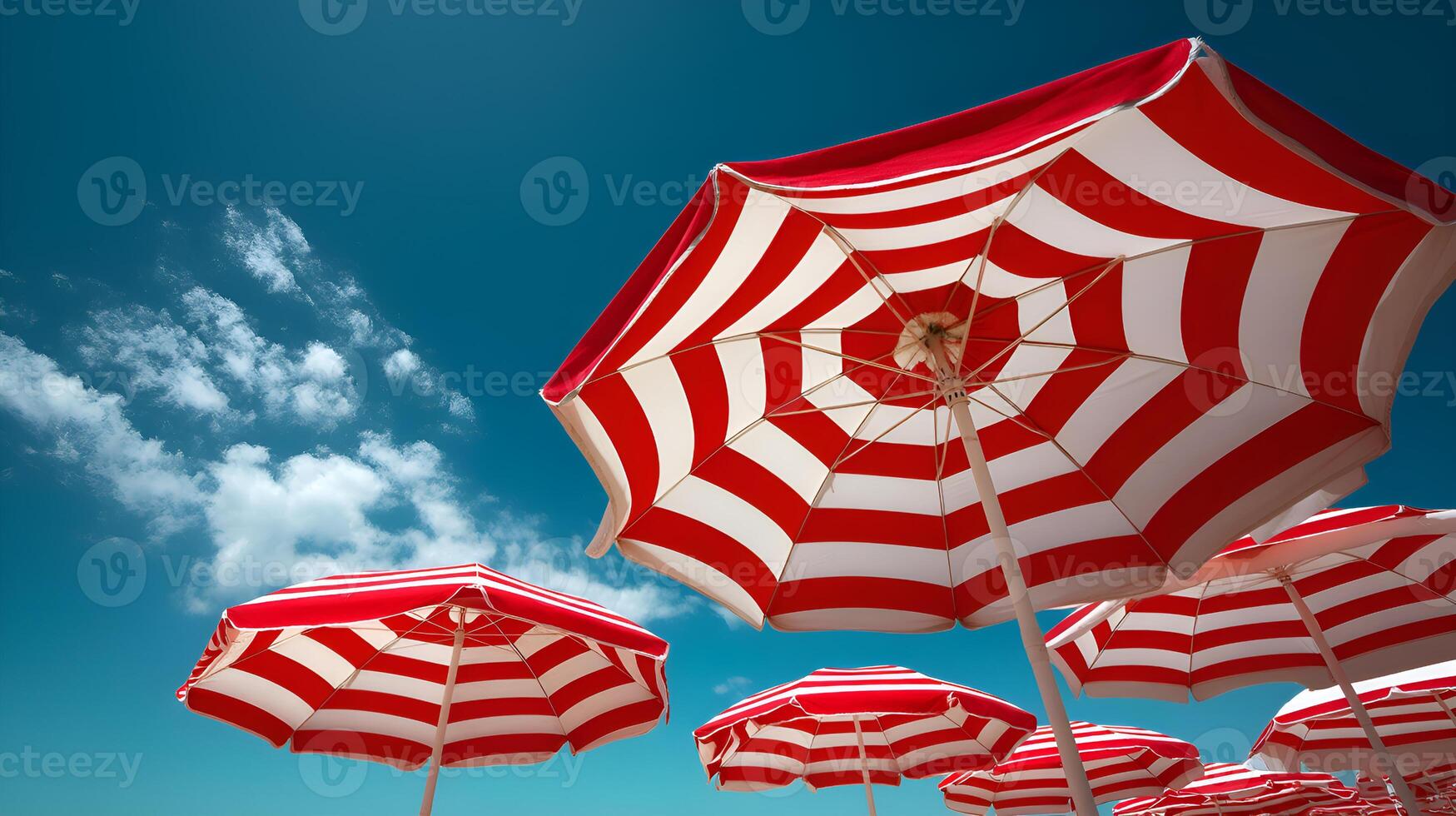 Red and white striped beach umbrellas under blue sky and clouds photo