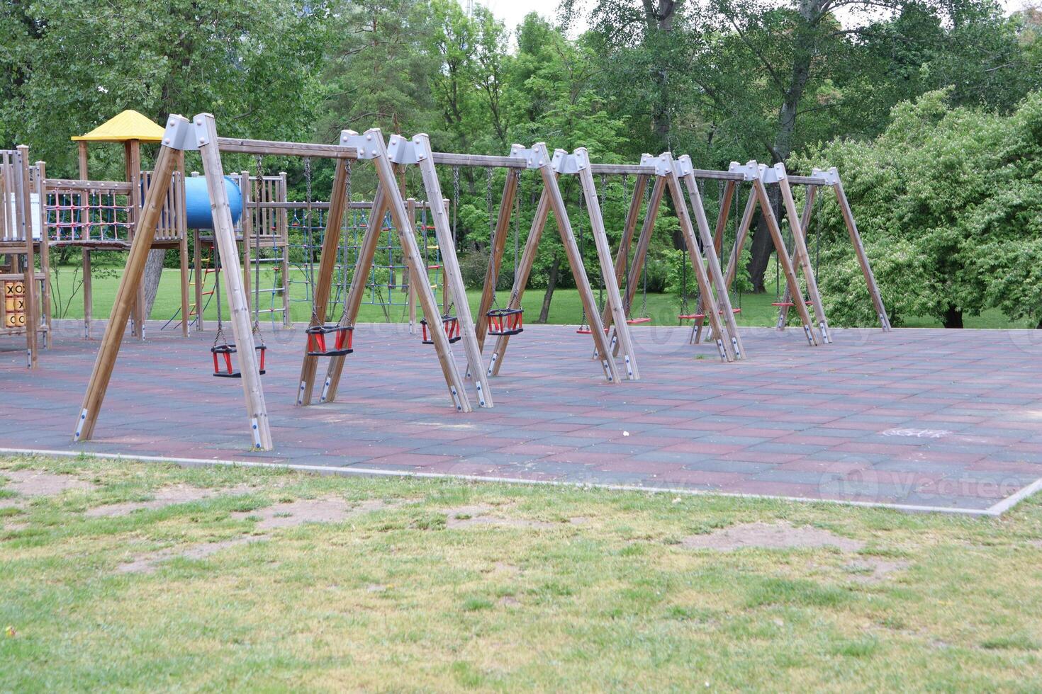 An Empty Playground Featuring Swings Amidst a Green Park Setting, Inviting Joyful Activities photo