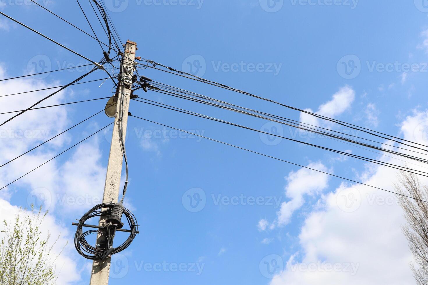 An Electric Pole Towering with Power Lines Against a Bright Blue Sky in the Background photo