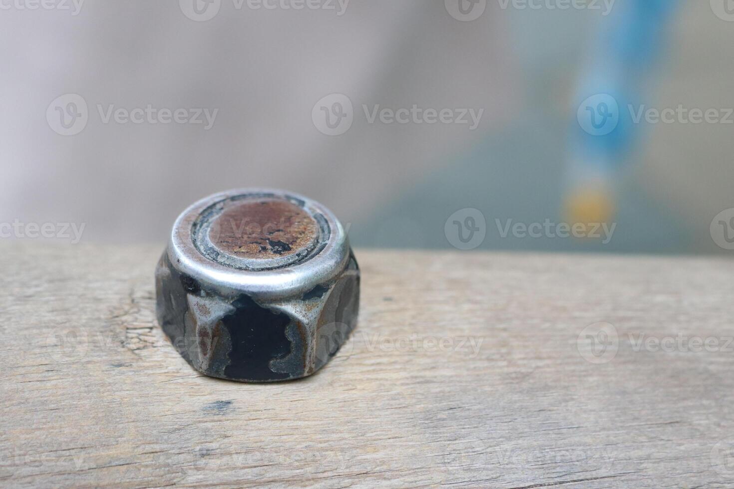A detailed closeup image of a used metal nut placed on a wooden surface for examination photo